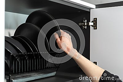 Person`s hand stacking black plates after washing Stock Photo