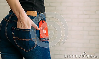 Cropped view slim woman in jeans with label black friday, copy space. Female hands in the back pocket of blue denim pants, close Stock Photo