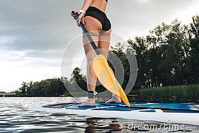 cropped view of tattooed girl standing on paddle board Stock Photo