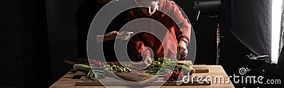 Cropped view of two photographers making food composition for commercial photography on smartphone, panoramic shot Stock Photo