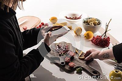 Cropped view of two photographers making food composition for commercial photography on smartphone on wooden table Stock Photo