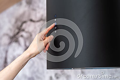 Woman hand select mode on black modern cooking hood Stock Photo