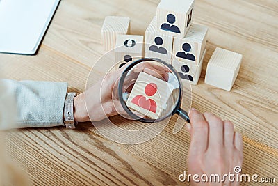 View of woman holding magnifier near wooden cube Stock Photo