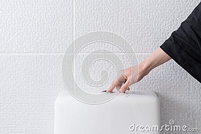 Woman`s hand pushing button and flushing toilet Stock Photo