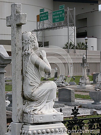 Cross and Funerary Statue and Cemetery with Interstate Roadsigns in the Background Stock Photo