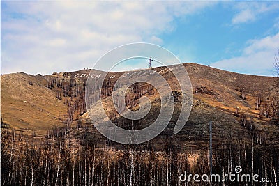 Cross and inscription on the mountain. Translation from Russian: bless and save. Karabash, zone of ecological disaster. Russia Stock Photo