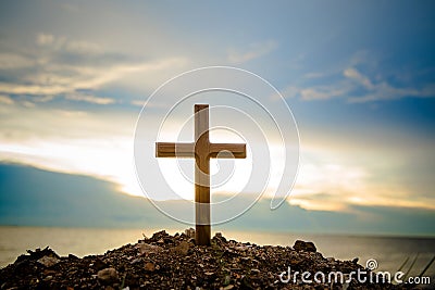 The cross standing on meadow sunset and flare background. Cross on a hill as the morning sun comes up for the day. Stock Photo