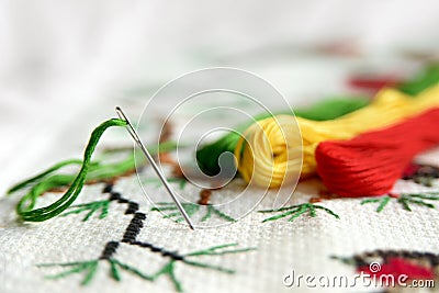 Cross-stitch embroidery and needle with red thread. Embroidery macro close up. Stock Photo