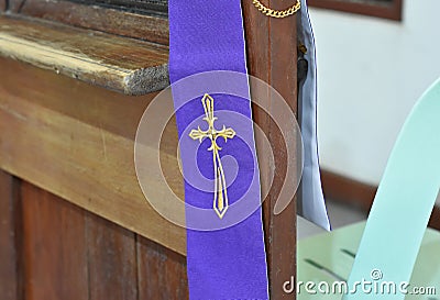 A cross symbol on a purple cloth for the priest is placed on a wooden platform for the confession of sins in Christianity Stock Photo