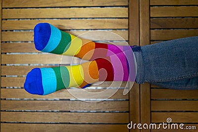 Crossed feet with pride socks on a wooden background Stock Photo