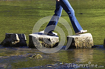 Crossing three stepping stones in a river Stock Photo