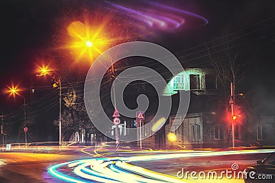 Crossroads of a lonely night provincial town. Red traffic lights in city. Headlight in motion blur Stock Photo