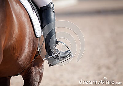 Croup of a red horse with a white saddle and a riderâ€™s foot in a boot with a spur inserted in a stirrup Stock Photo