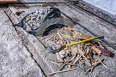 Crowbar on construction waste debris in black plastic bag and on old concrete floor, demolished room, close up view Stock Photo