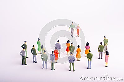 The crowd looks at the man and woman who comes towards her on a white background. A man and a woman are approaching a group of peo Stock Photo