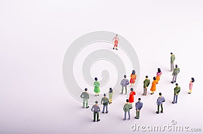 The crowd looks at the woman who is walking towards her on a white background. A woman is approaching a group of people. Leader of Stock Photo