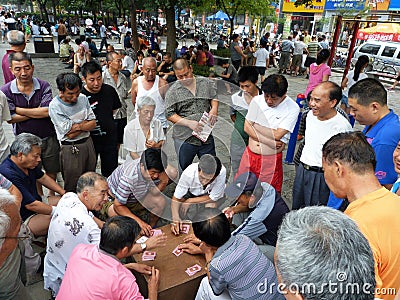 Crowd of onlookers watching a card game in a public square China. Editorial Stock Photo