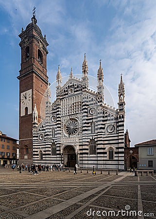 Crowd of people ambling past the towering Monza Cathedral on a sunny day. Italy. Editorial Stock Photo