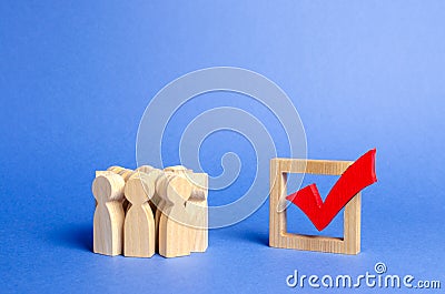 Crowd of people looking at a red wooden checkmark for voting on elections on a blue background. Presidency or parliamentary Stock Photo