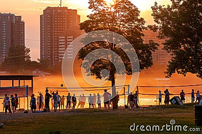 Crowd of people playing volleyball through a hot and hazy sunset Editorial Stock Photo