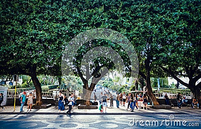 Crowd of people walking on street with green trees of city park Giardino Bellini Editorial Stock Photo