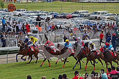 Crowd of spectators, cars & jockeys riding horses fast and speedy at Champ de Mars Racecourse Editorial Stock Photo