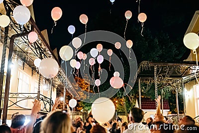 Crowd Throwing Colorful Balloons to Sky at night During Festival or wedding party Stock Photo