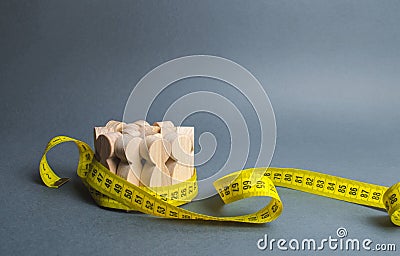 A crowd of wooden figures Gripped by measuring tape. Information statistics, measurement of the number, trends of population Stock Photo