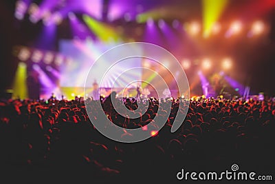 A crowded concert hall with scene stage lights, rock show performance, with people silhouette, colourful confetti explosion fired Editorial Stock Photo