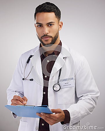 A crowded space and no mask Tsk Tsk. a handsome young doctor standing alone in the studio and writing on a clipboard. Stock Photo