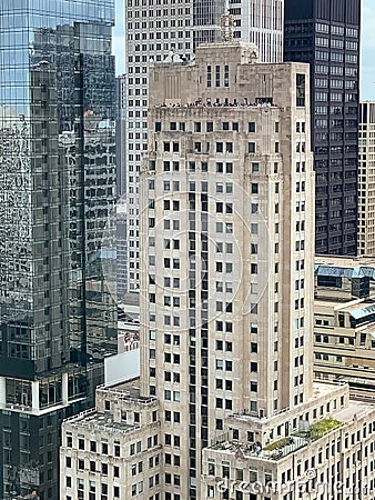 Croweds of people gather on a rooftop deck and a mid-building deck Stock Photo