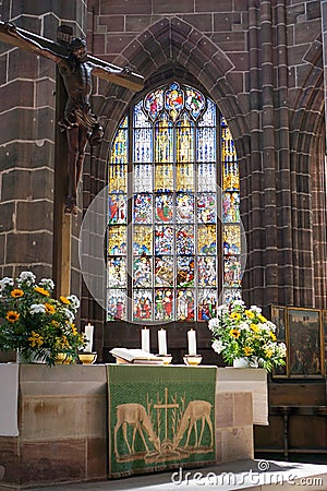 Crucifix, altar, and stained glass window inside of a church Stock Photo