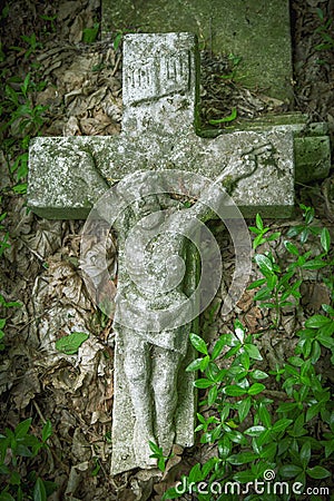 The crucifixion of Jesus Christ. Very old and ancient stone destroyed statue in the grass. Vertival image Stock Photo