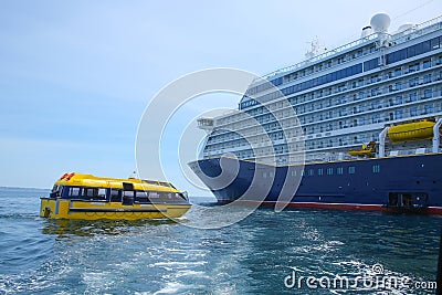Cruise ship at anchor ourside St Peter Port, Guernsey. Large ship with blue hull and a yellow lifeboat or tenders. Stock Photo