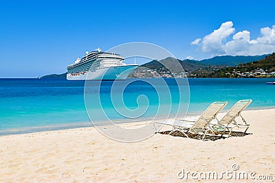 Cruise ship in Caribbean Sea with beach chairs on white sandy beach. Summer travel concept. Stock Photo