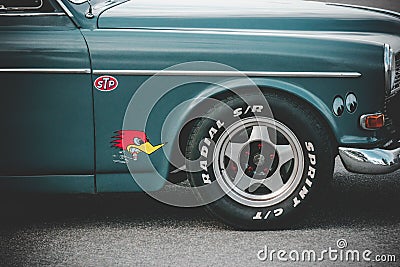 A closeup shot of the side of a green vintage car with stickers above the wheel Editorial Stock Photo