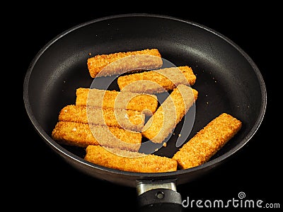 Crumbed fish fingers in fry pan Stock Photo