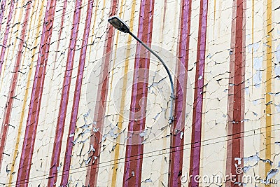 The crumbling flaking old paintwork on an old and aging wall of tenement house with street lamp. The painting begins to fade and Stock Photo