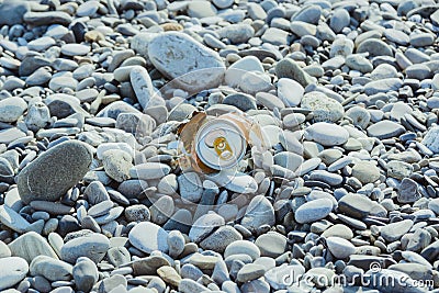 Crumpled aluminum metal orange can on pebble beach Stock Photo