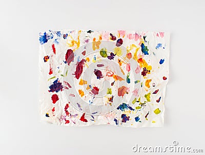 Crumpled paper splattered with vibrant multicolor paint on white background. Minimal composition. Flat lay Stock Photo