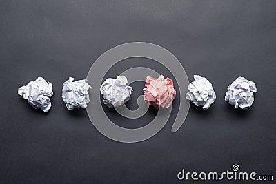 Crumpled pink paper ball among white balls Stock Photo
