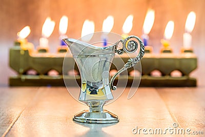 Cruse of oil made of silver, Hanukkah. with A stone menorah and candles background Stock Photo