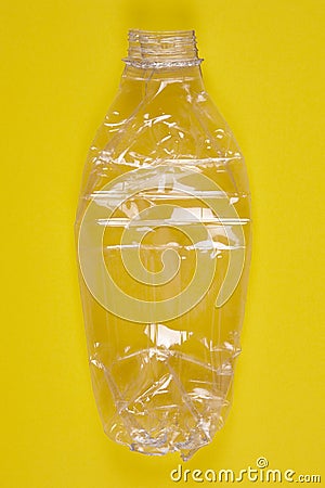 Crushed plastic bottle with yellow background. Recycled garbage. Stock Photo