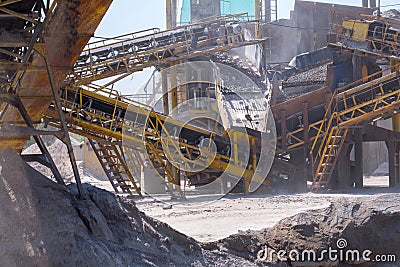 Crushing machinery, cone type stone crusher, conveying crushed granite gravel stone in a quarry open pit mining. Processing plant Stock Photo