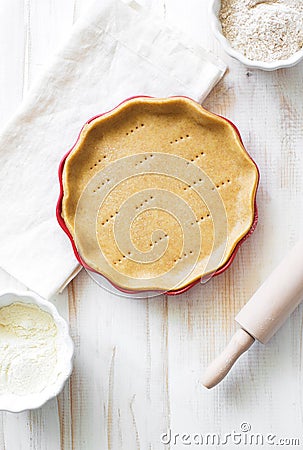 Crust on baking sheet , pots with wheat and bran flour and rolling pin on white wooden table Stock Photo