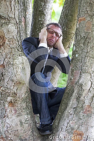 Crying businessman climbing in a tree for mother earth protection Stock Photo