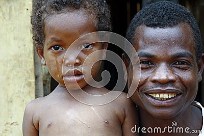 Crying girl with tear on cheek with smiling father - poor africa Stock Photo