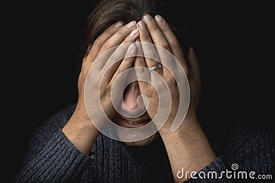 Crying man suffers and covers his face with hands. Depression, mental pain, tragedy, problems in life and grief concept Stock Photo