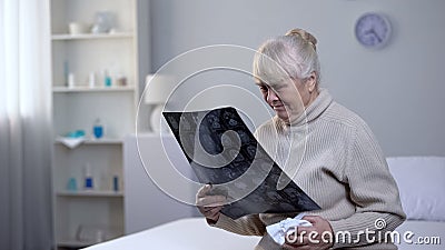 Crying old lady looking at brain x-ray in hospital, incurable disease, health Stock Photo