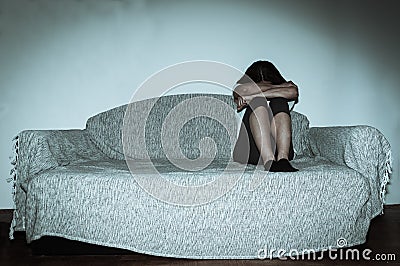 Crying woman abused as young feeling depressed and miserable while she sitting alone in her room Stock Photo